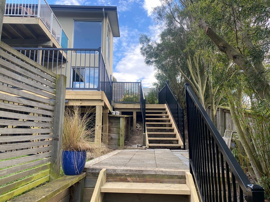 New timber deck with a horizontal slat privacy screen and steps down to a paved patio
