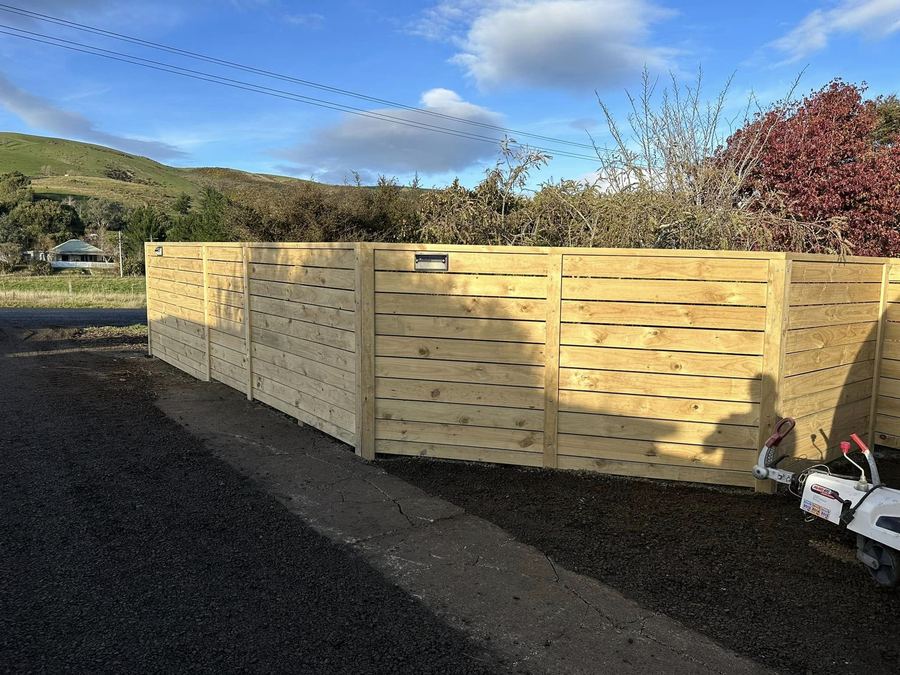 Horizontal 150mm timber board fence beside a driveway with hills behind