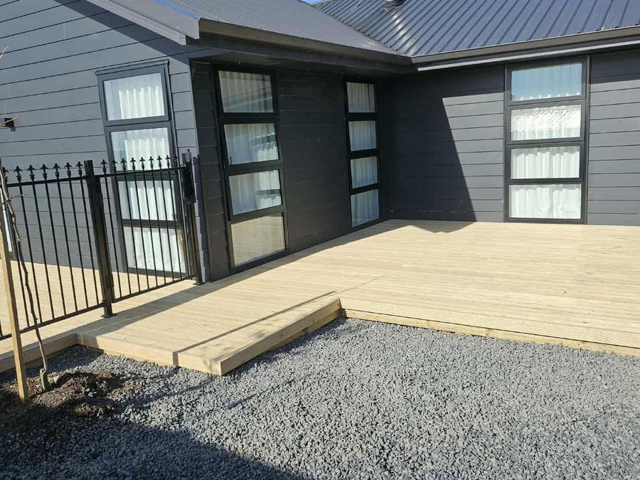 Black steel pool fence enclosing a new timber deck at a dark modern house