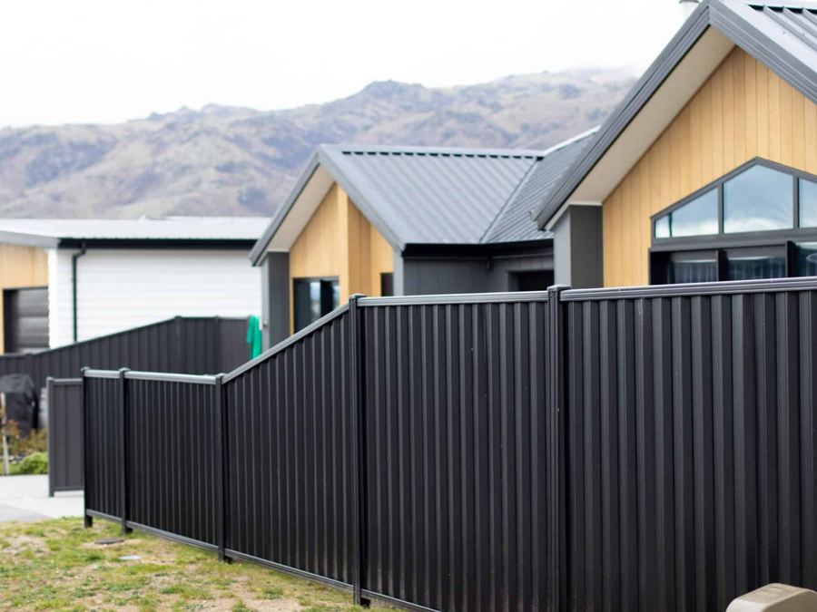 Dark colour steel fence panels along a new subdivision boundary with hills behind