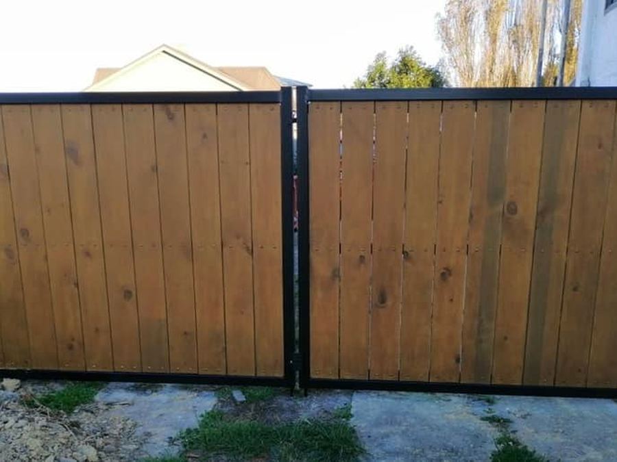 Twin stained timber driveway gates hung in black steel frames