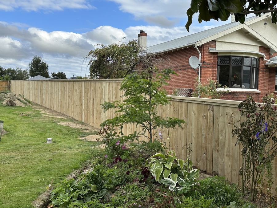 Timber paling fence enclosing the garden of a brick bungalow