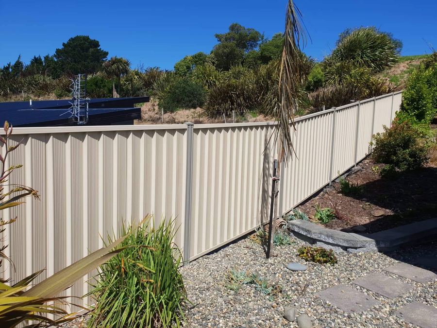 Cream colour steel fence panels stepping down a planted slope