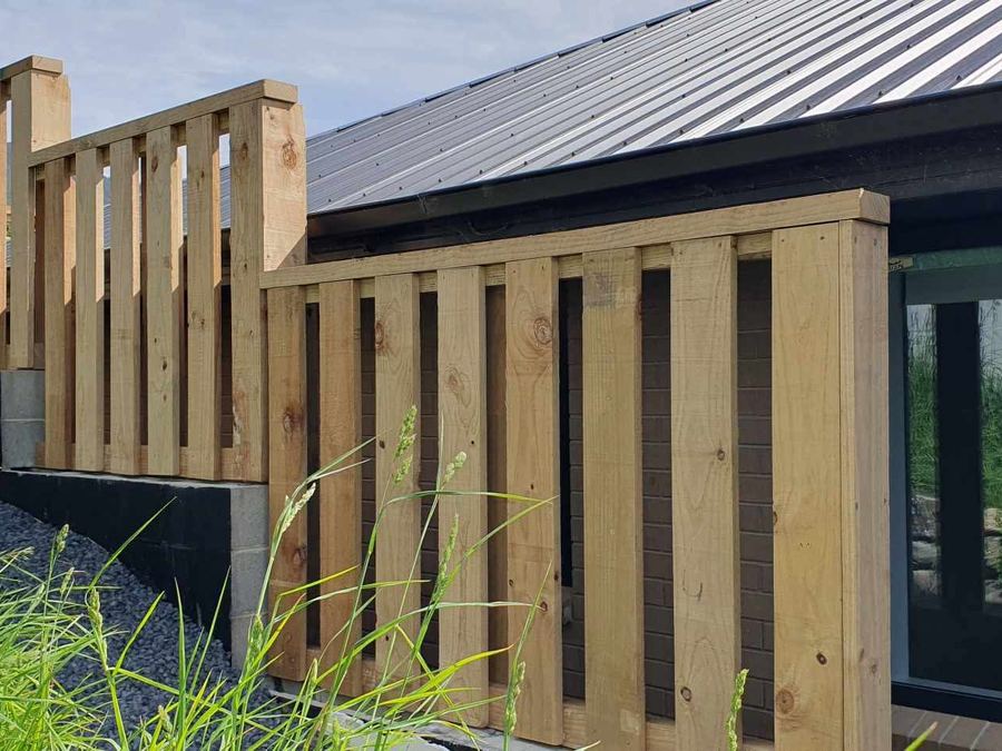 Timber balustrade and screen built along the edge of a deck at a modern dark-clad house