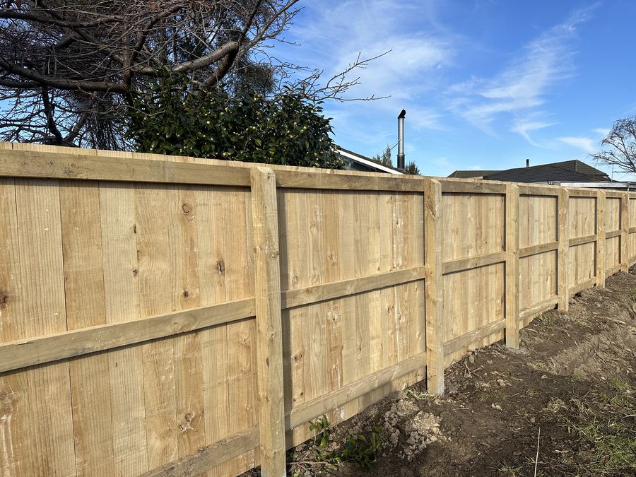 Timber paling fence with rails photographed against a blue sky