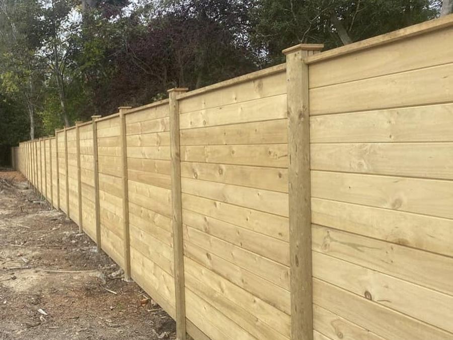 Long run of horizontal wide-board timber fencing on a newly finished section