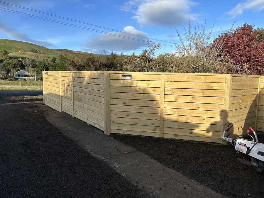 Horizontal timber board fence enclosing a yard with Otago hills behind