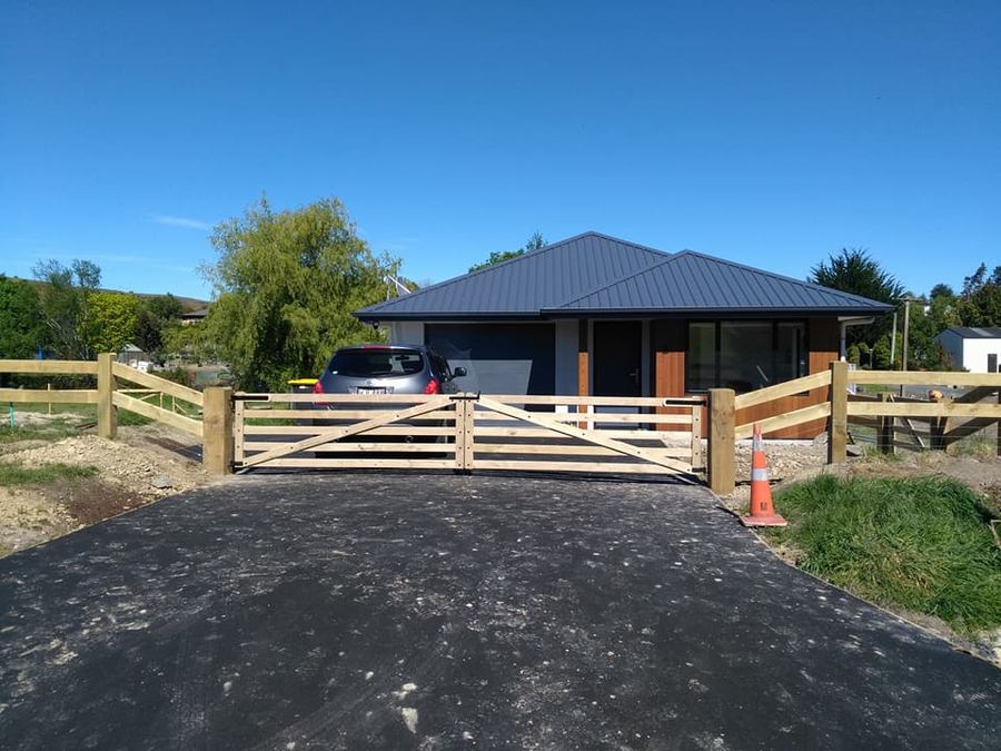 Post and rail fence and timber entrance gate at a modern house