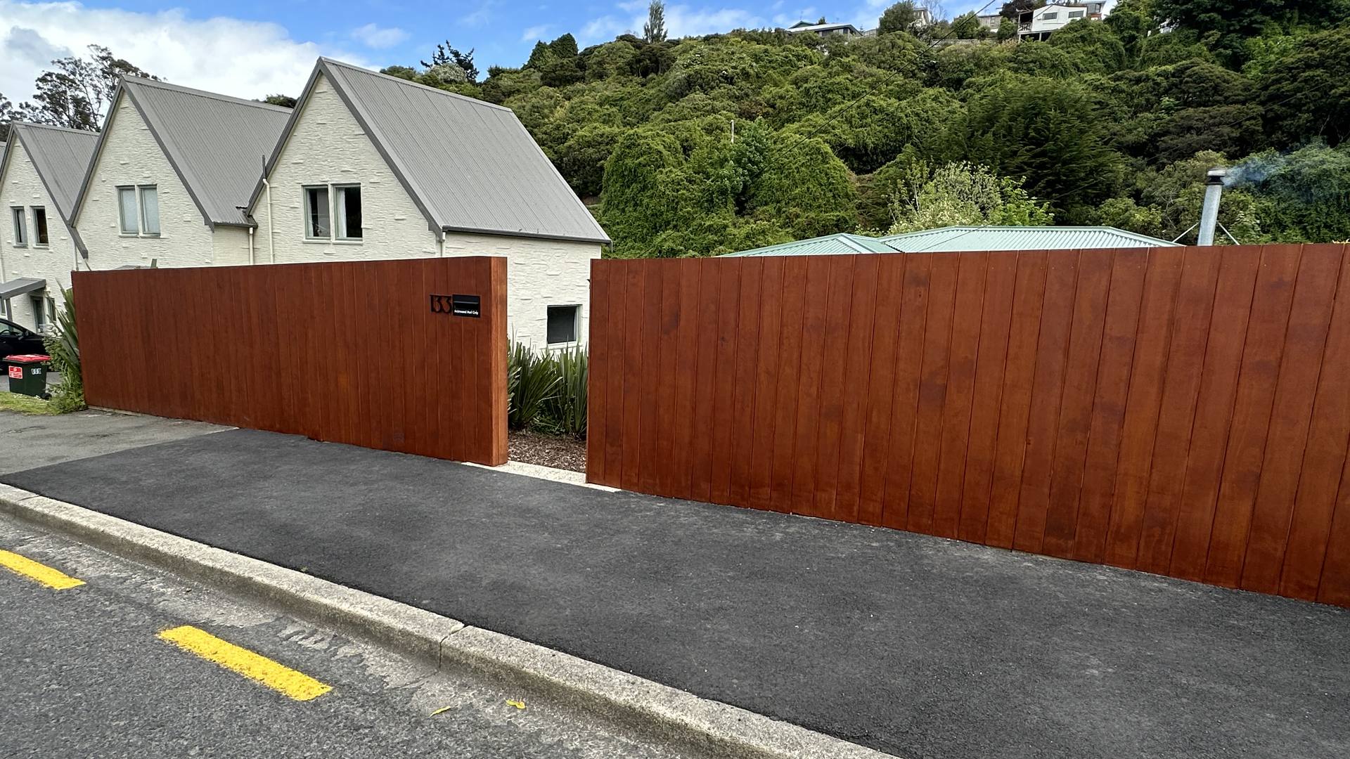 Dark stained timber paling fence running the length of a townhouse driveway