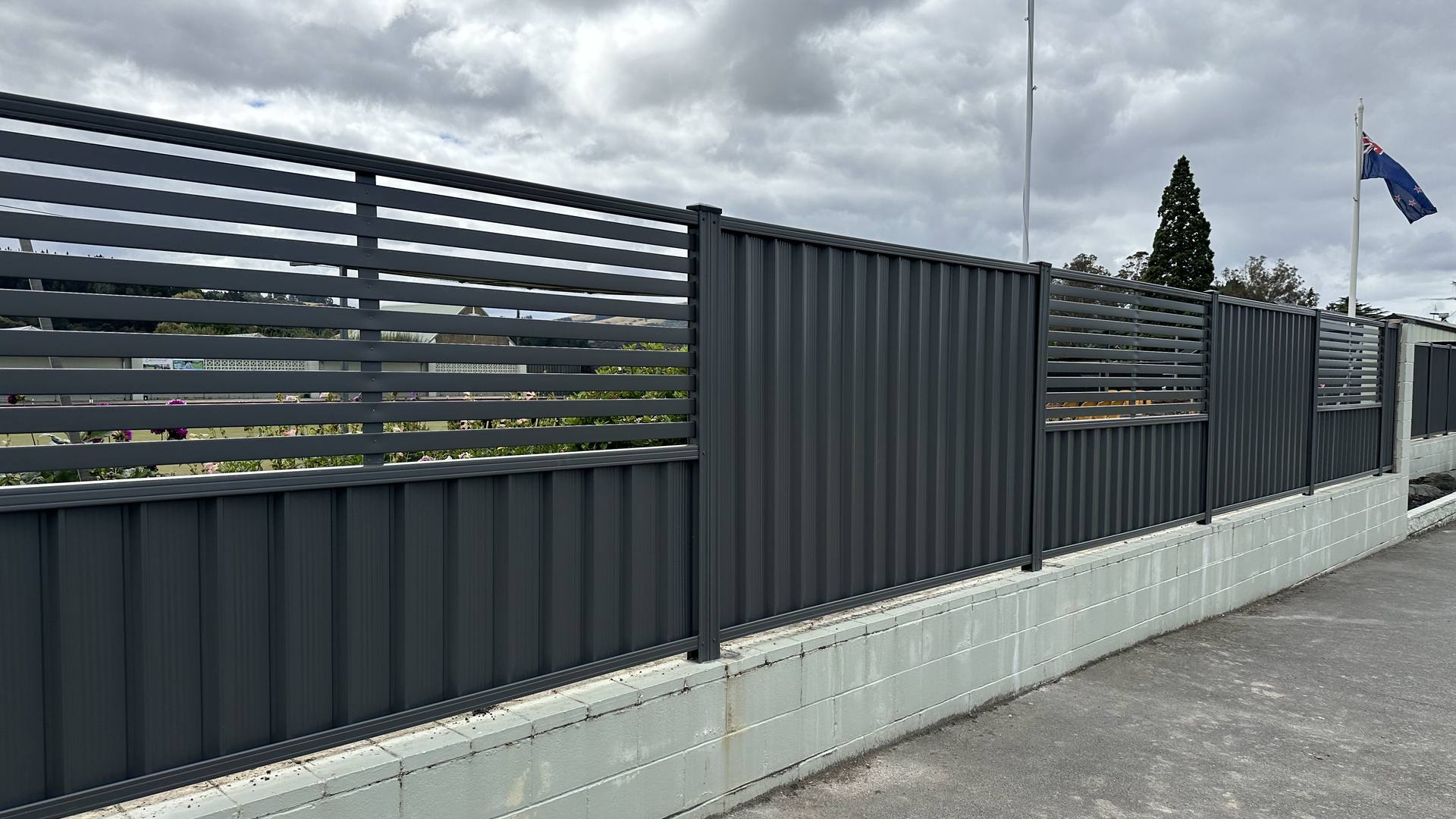Charcoal colour steel fence with a horizontal slat top section along a commercial boundary