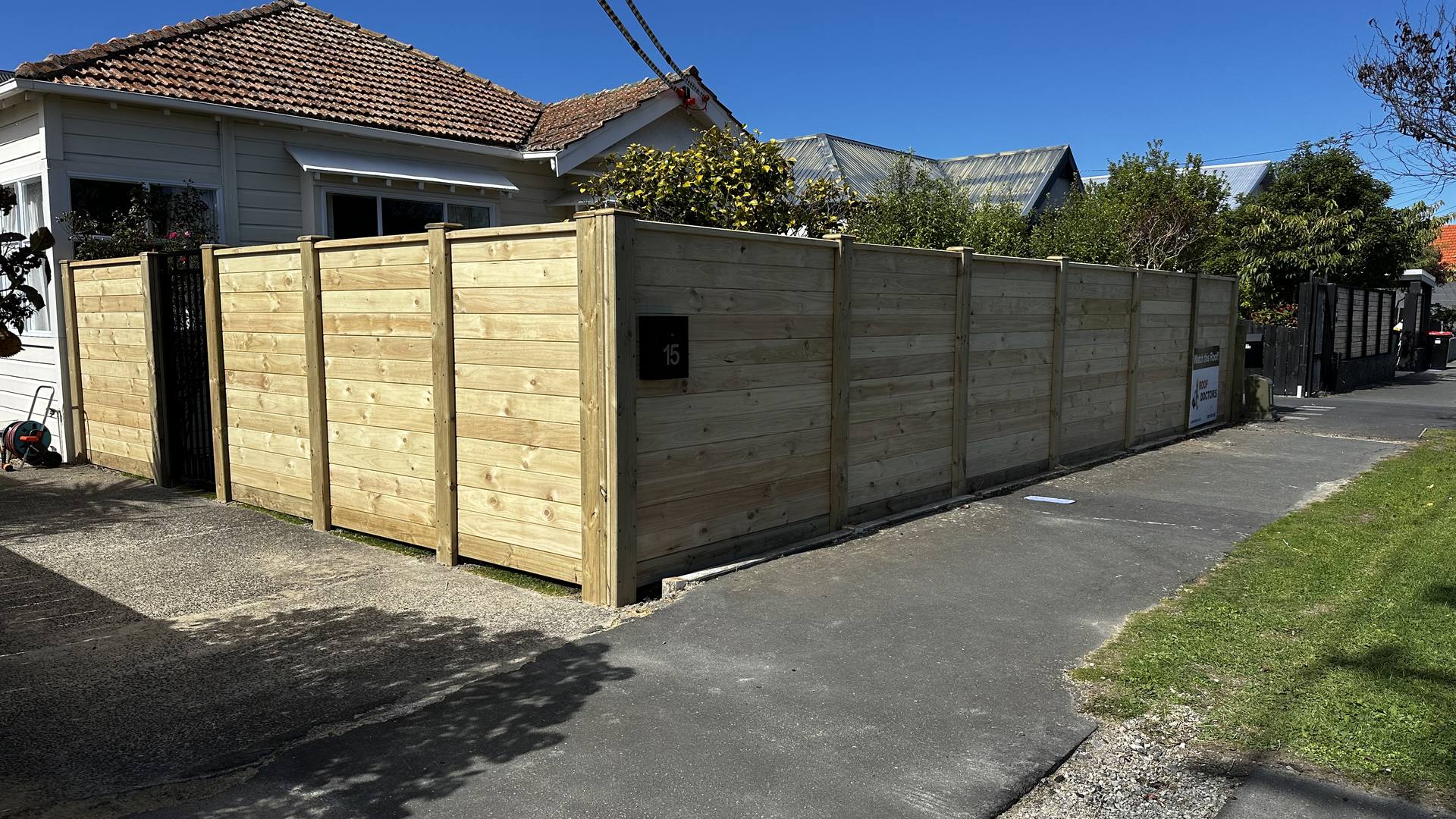 Horizontal timber fence and gate running the length of a driveway