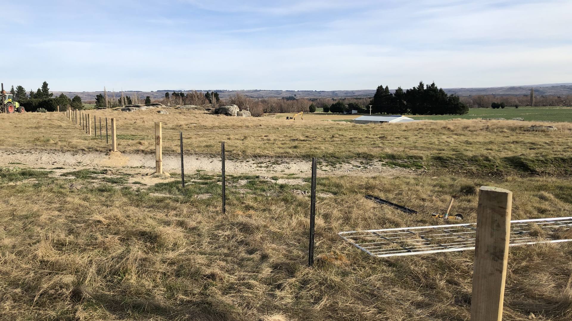 Farm fence line running across a dry Otago paddock under a wide sky