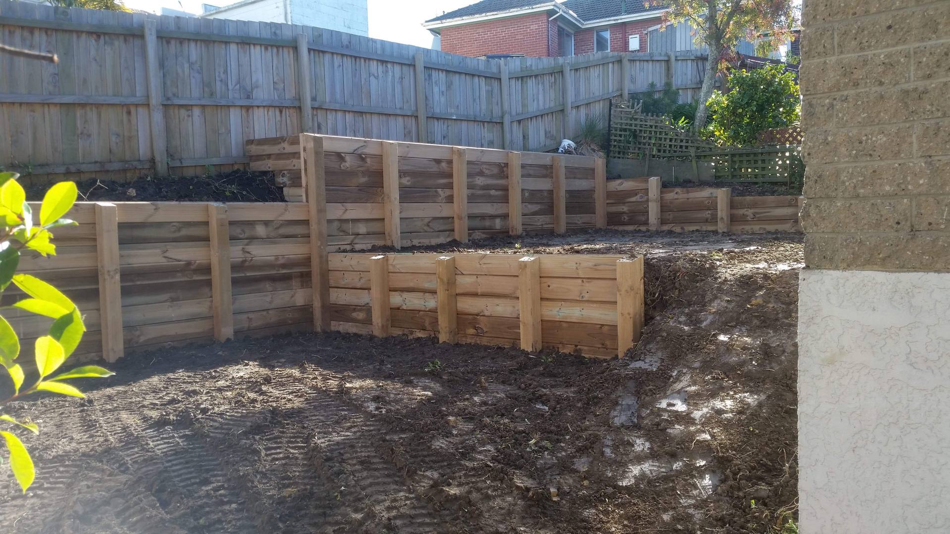 Terraced timber sleeper retaining wall holding a bank behind a house